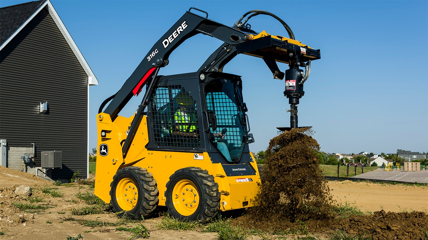 Carretilla Elevadora 316G con un accesorio de Sinfín excavando un hoyo