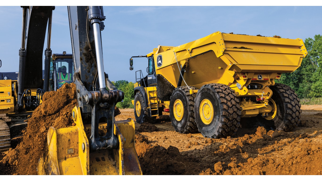 Un camión volquete articulado 410P esperando ser cargado con tierra de una excavadora cercana.