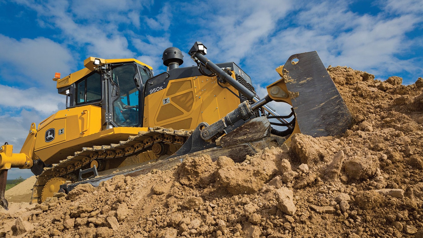 Un primer plano de un bulldozer 950K empujando tierra encima de una reserva.