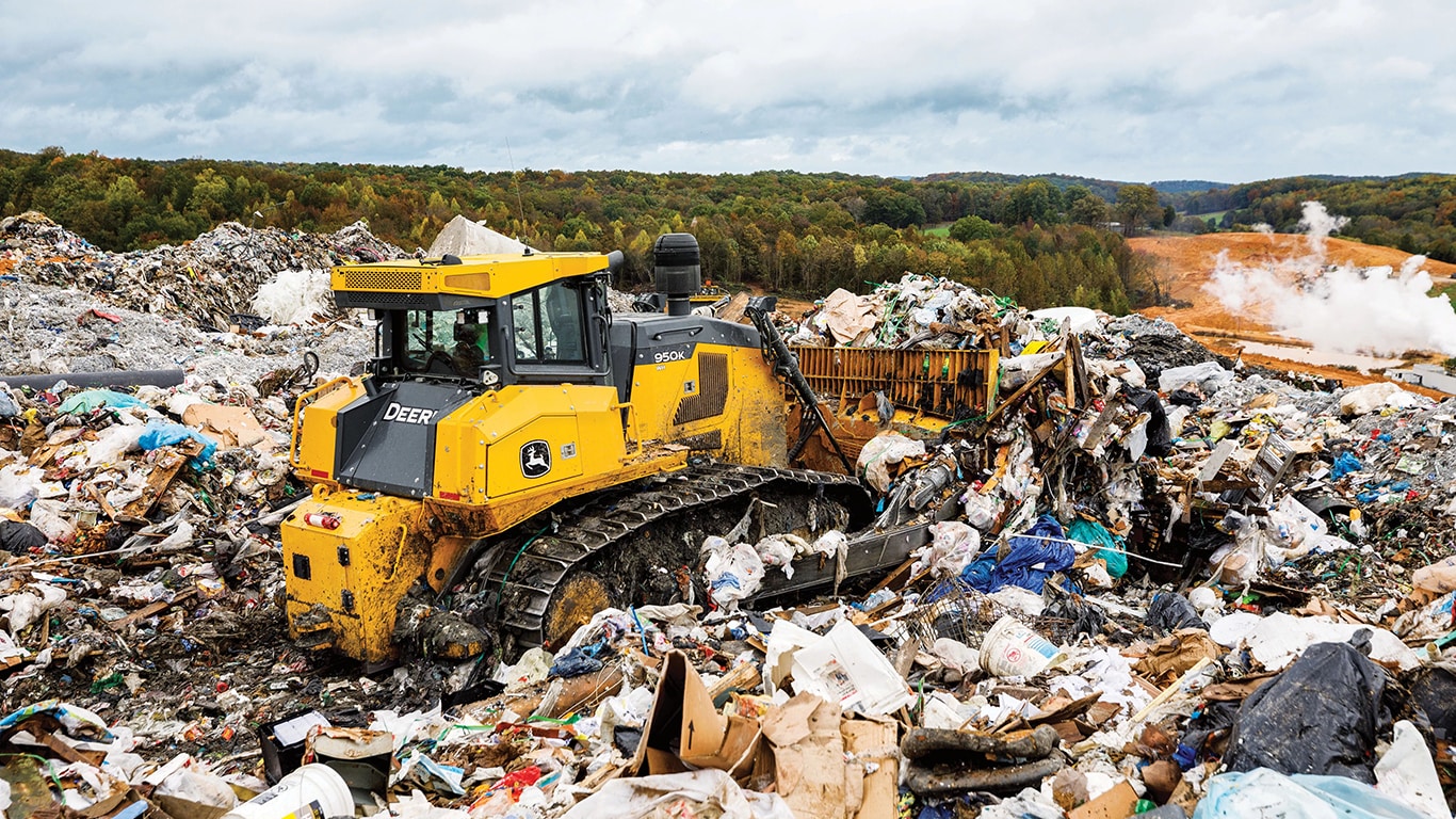 Un bulldozer 950K empuja la basura en montones en un vertedero.