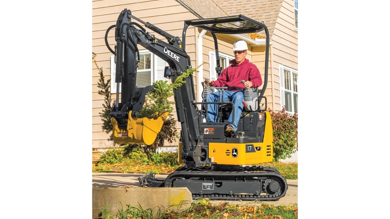 Hombre empleando la Excavadora 17P para remover plantas frente a una casa.