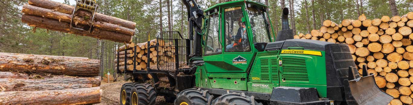 John Deere 1210G Forwarder loading logs from a pile onto the log truck