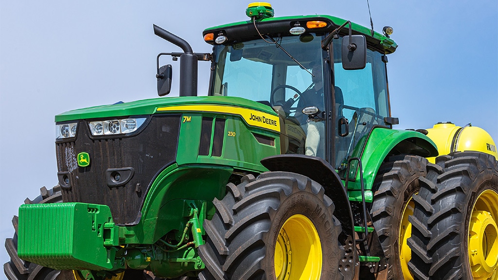 Tractor John Deere de alta potencia sobre un terreno rural, en perspectiva frontal.