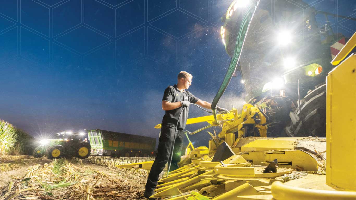 Un hombre frente a un helicóptero John Deere por la noche.
