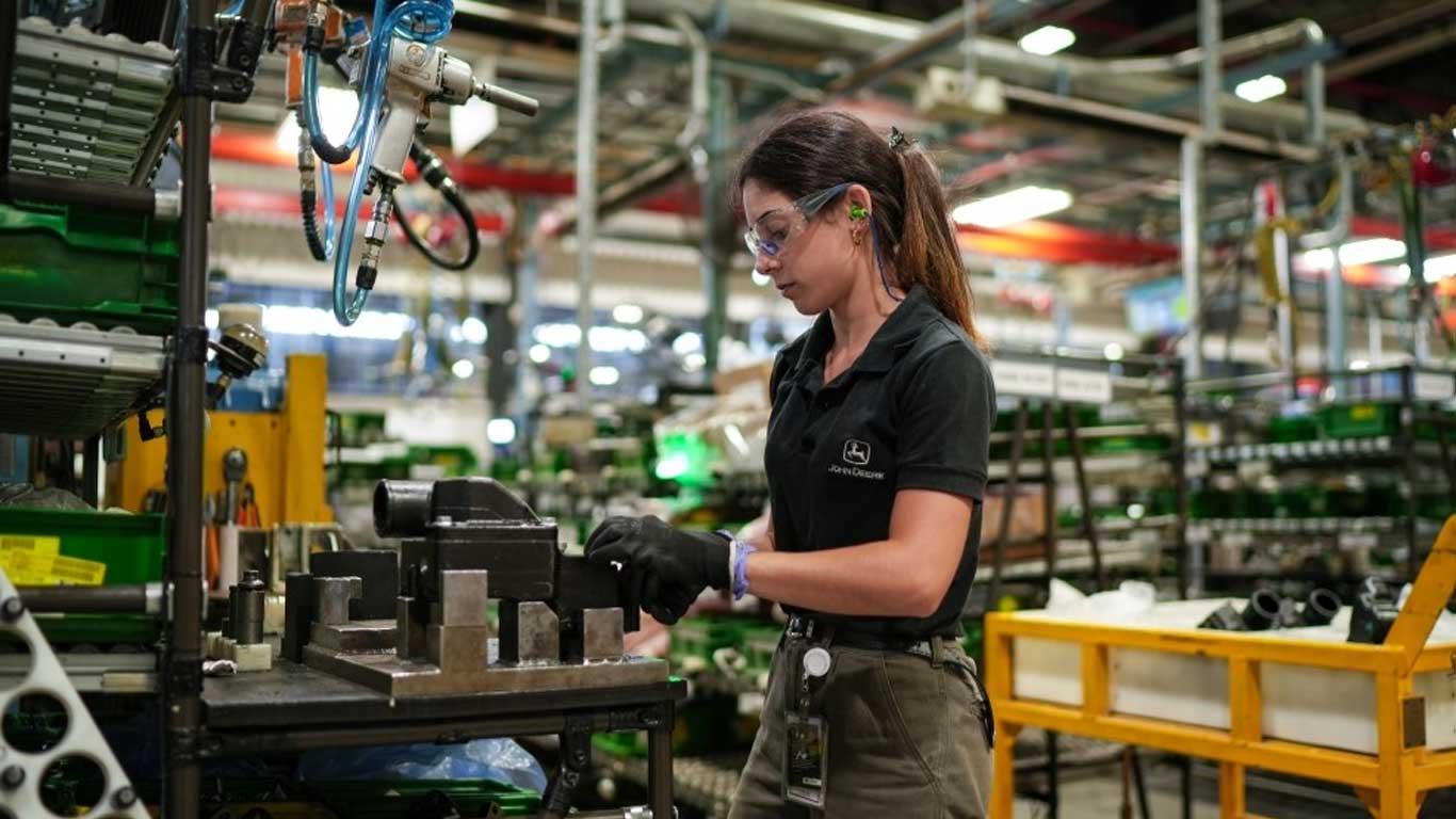 Mujer con elementos de seguridad y uniforme John Deere trabajando en la fábrica de John Deere Argentina