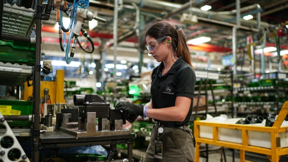 Mujer con elementos de seguridad y uniforme John Deere trabajando en la fábrica de John Deere Argentina