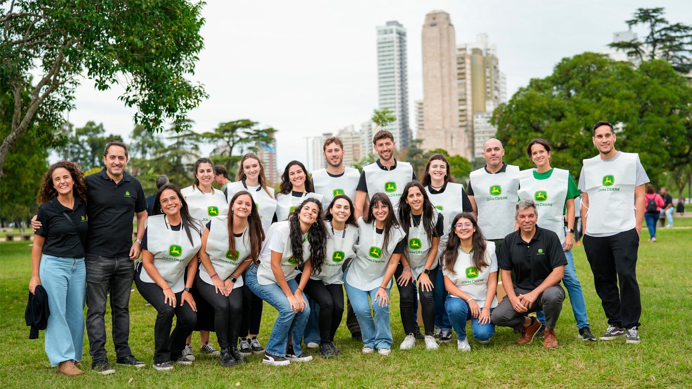 Grupo de voluntarios con chalecos John Deere en un parque