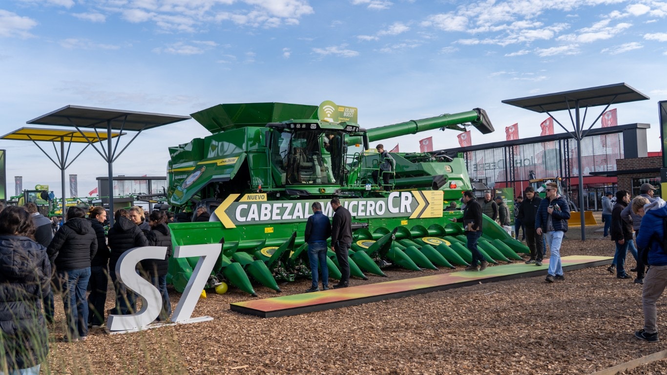Visitantes recorren una cosechadora John Deere con cabezal maicero CR exhibida en una exposición agrícola Agroactiva.