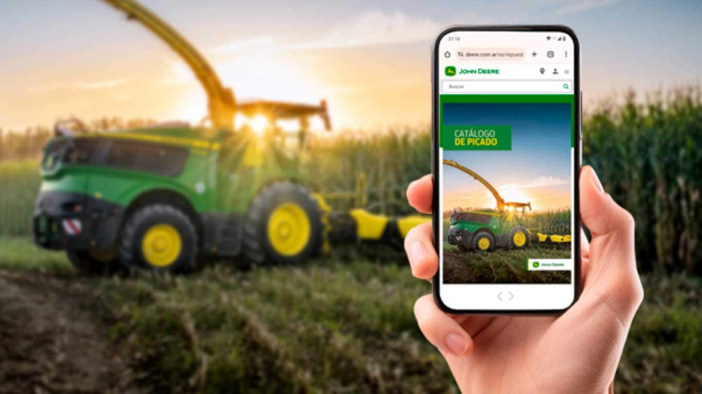 Al fondo una máquina John Deere en el campo, y al frente un celular con el Catálogo de Picado.