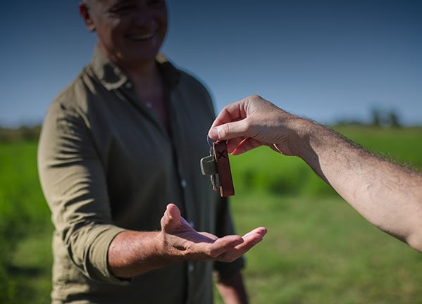 Una mano entregando una llave a un hombre en el campo.