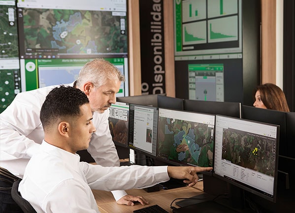 Dos hombres observando una computadora con dos pantallas en el Centro de Soluciones Conectadas.