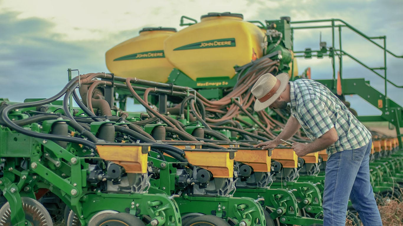 Un hombre manipulando una sembradora John Deere