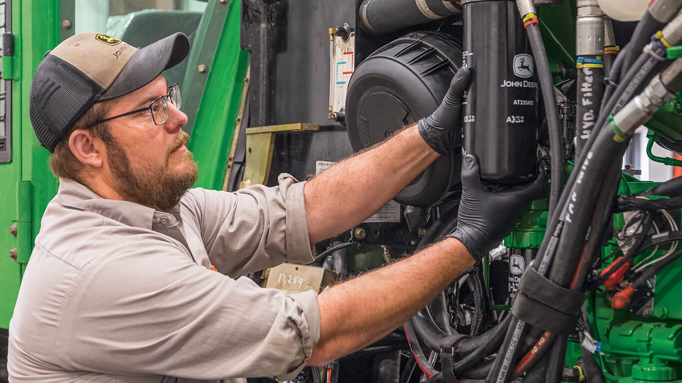 Técnico de mantenimiento de la máquina John Deere y sustitución del filtro